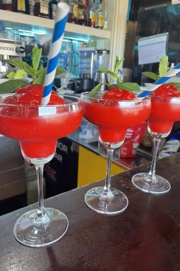 Tres cócteles de fresa helados en copa, en la barra